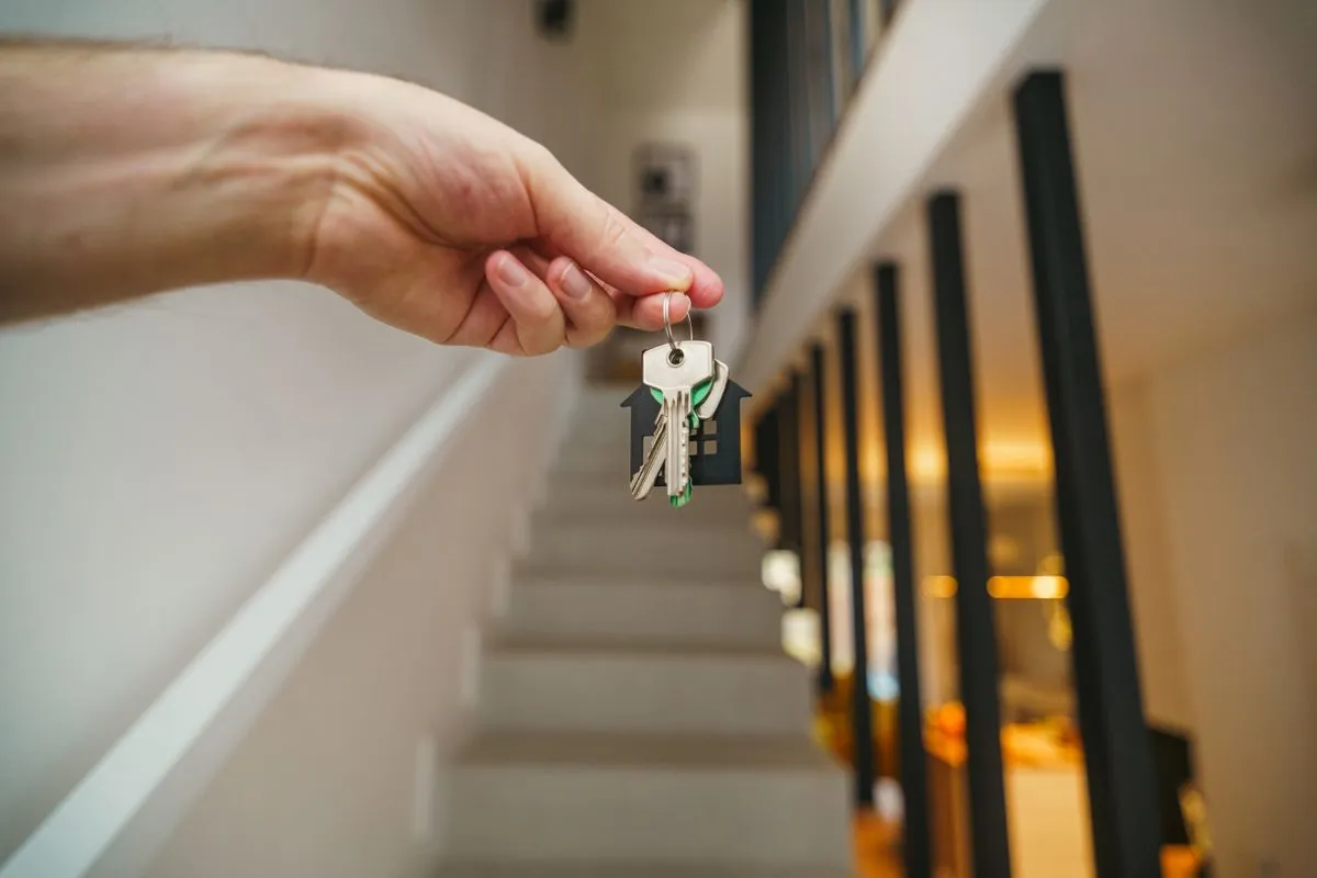 House keys held in a modern rental interior