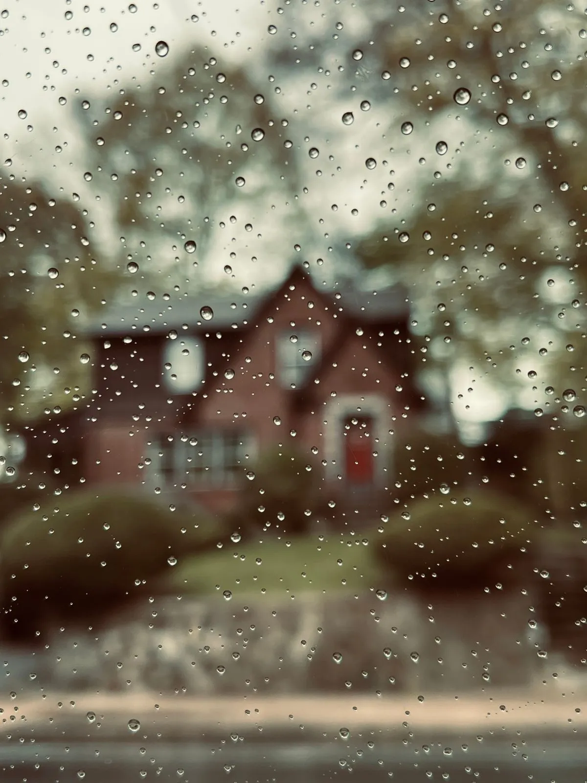 Maison vue à travers une fenêtre couverte de pluie