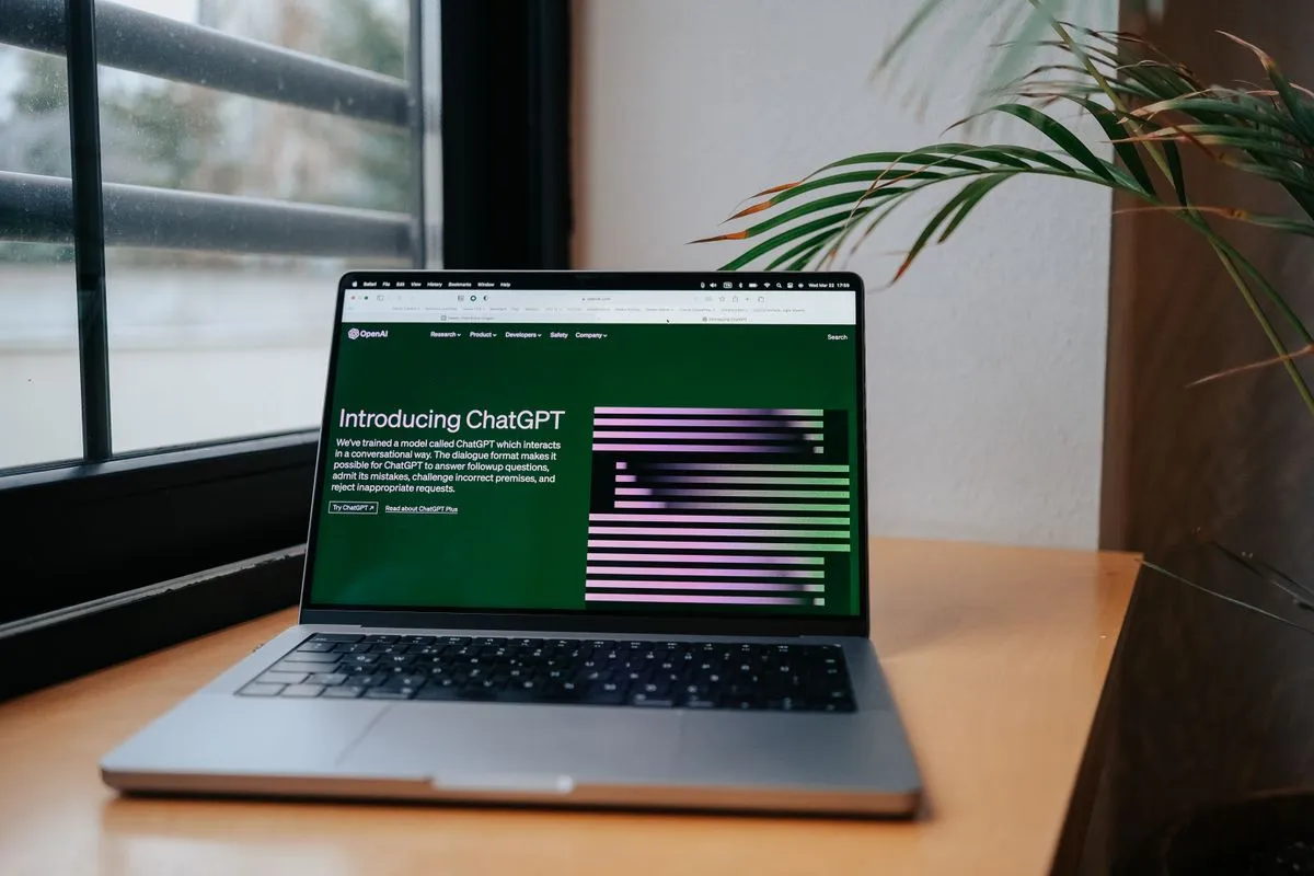 Laptop on a desk by a window displaying the ChatGPT page, as a host looks into connecting an AI assistant to Airbnb bookings