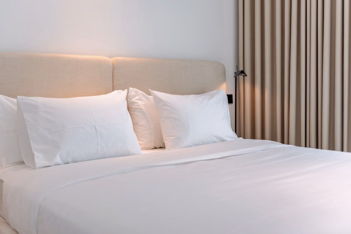 Freshly made bed with white linen in a holiday rental, the kind of stay hosts list on Booking.com
