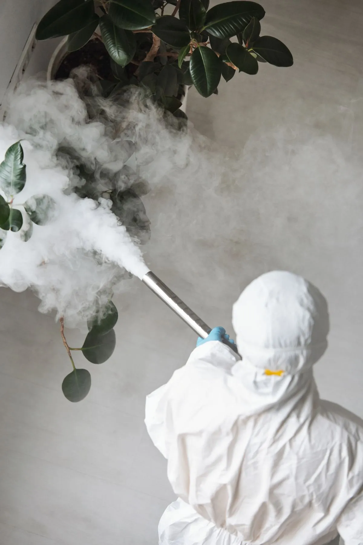 Pest control professional in protective gear treating an indoor space