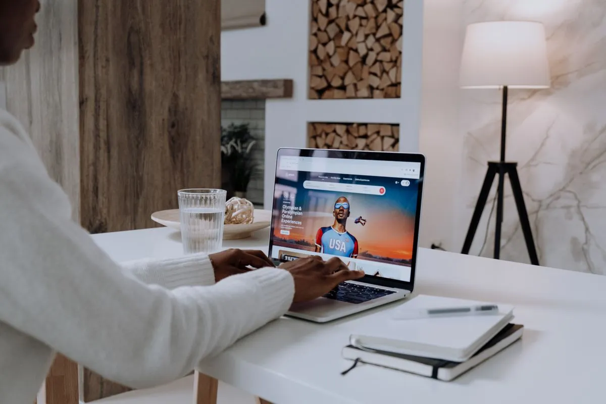 Voyageur tapant sur un ordinateur portable ouvert sur la page d'accueil d'Airbnb, point de départ d'une recherche assistée par l'IA