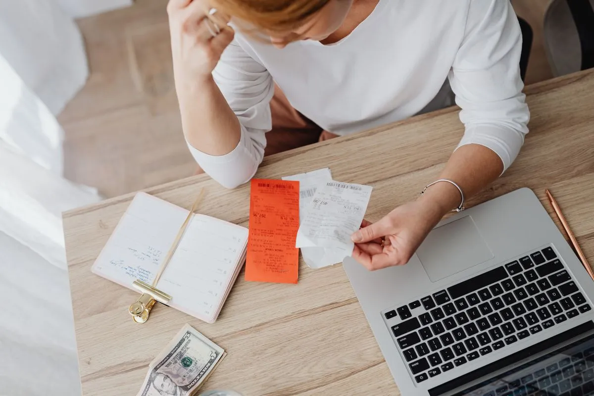Holiday rental owner checking invoices and receipts next to a laptop while preparing for French e-invoicing