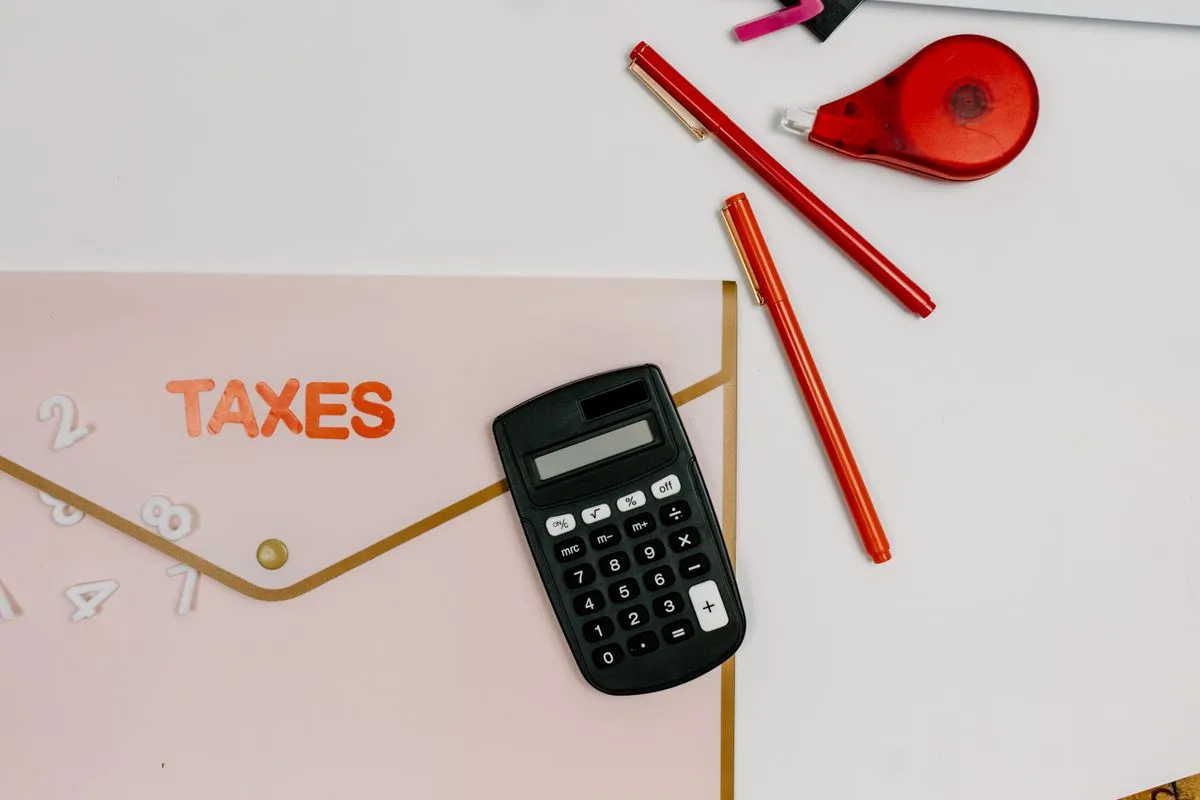 Calculator and red pens next to a folder labelled Taxes, as an owner prepares the CFE and local taxes on a holiday rental