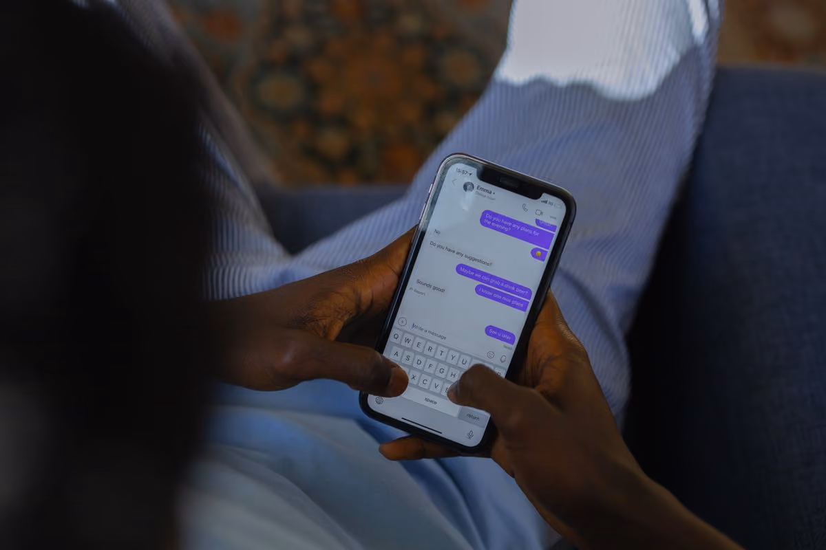 Hands typing a reply in a messaging app on a smartphone, like a host checking an AI-written guest message