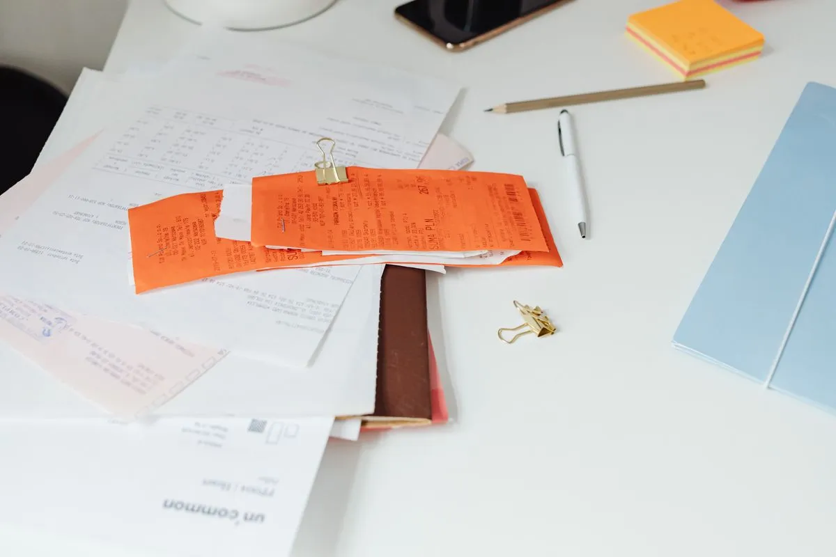 Stack of invoices and receipts on a desk, illustrating conciergerie invoices to property owners and guests