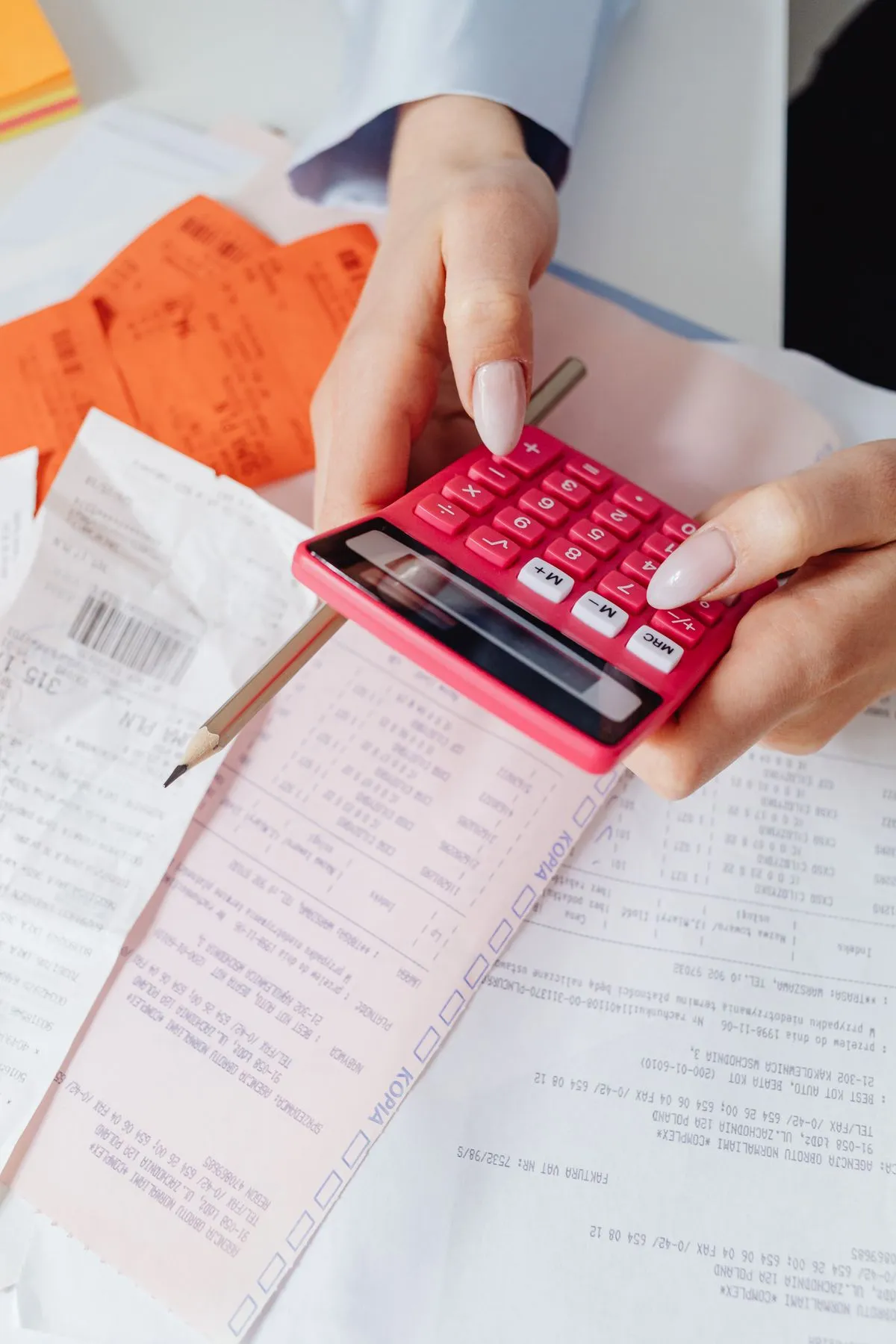 Host calculating a Booking.com payout with a calculator over printed statements and receipts