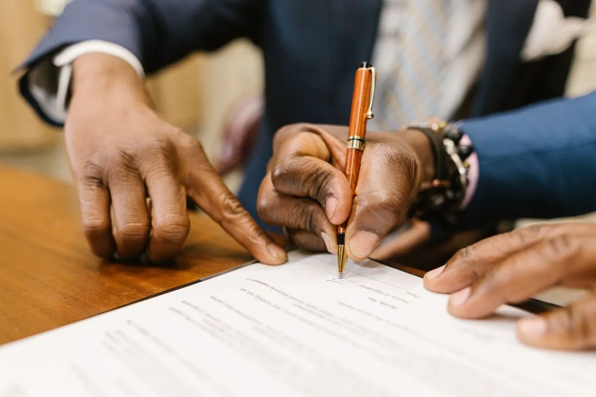 Close-up of a person signing a contract with a pen, as an owner and a concierge sign a management agreement that covers Airbnb access